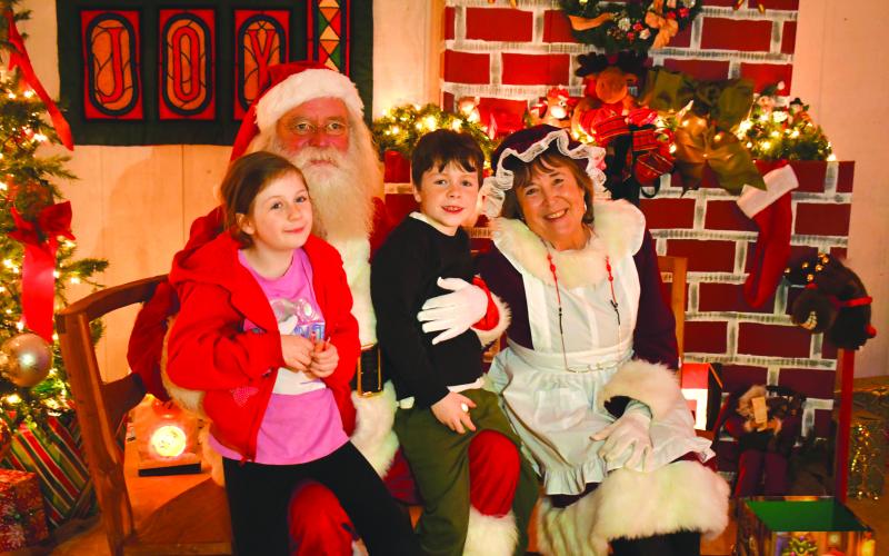 Megan Broome/The Clayton Tribune. Cora Blitch, 10, and Jason Blitch, 7, visit Santa and Mrs. Claus and discuss what they want for Christmas this year at FAITH’s Christmas Village of Lights display two weeks ago in Rabun County.