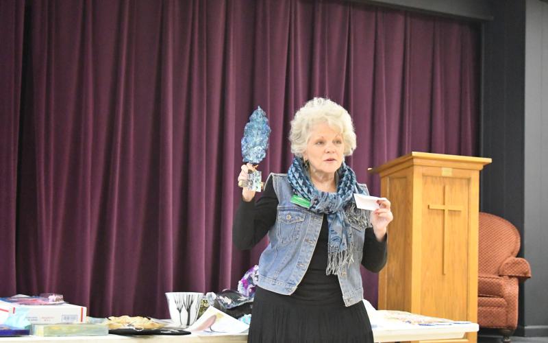 Megan Broome/The Clayton Tribune. North Georgia Arts Guild member Cynthia D'Angelo show her art piece and discusses painting on bark during the Feb. 16 Show and Tell event.