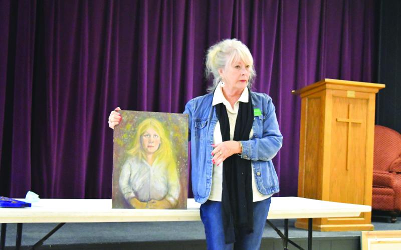 Megan Broome/The Clayton Tribune. North Georgia Arts Guild member Teresa Weiser displays one of her paintings at the member’s showcase Feb. 16. Weiser said that although the piece is unfinished, she “put herself out there” and feels confident displaying her works among peers. Weiser’s chosen medium is painting.