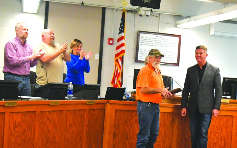 Megan Broome/The Clayton Tribune. Clayton Mayor Kurt Cannon, right, presents Streets Department worker Everiest Turpin with a plaque thanking him for his years of service to the city after he announced his retirement. Turpin received a standing ovation from council members and attendees, and pictured are council members Woody Blalock and David Cross and City Manager Trudy Crunkleton congratulate Turpin during his 18th year of service.