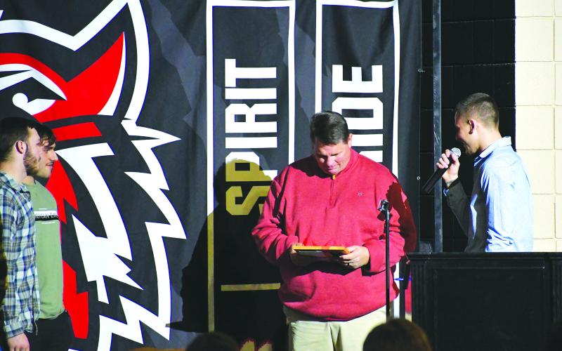 Luke Morey/The Clayton Tribune. During the Football Awards Banquet, senior Noah Legault (right) led the group of 19 Rabun County seniors who surprised head coach Michael Davis with a photo of the seniors’ favorite memory of Davis.