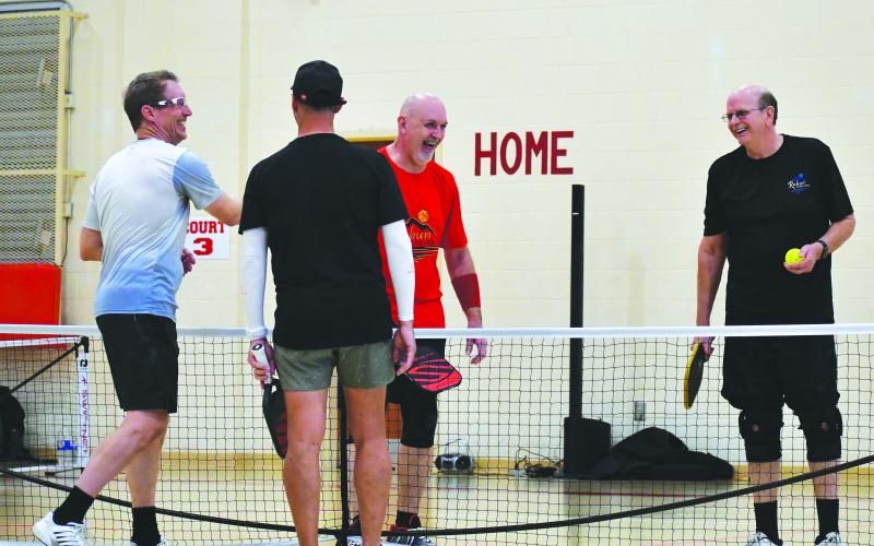 Luke Morey/The Clayton Tribune. Rabun Pickleball Club members Roy Quilliams, left, and Danny Burch share a laugh with professsionals David Spearman, in blue, and Mark Price. Quilliams, who is the director of the Rabun County Recreation Department, teamed up with Burch to take on the professionals during the showcase on Sunday, March 5.