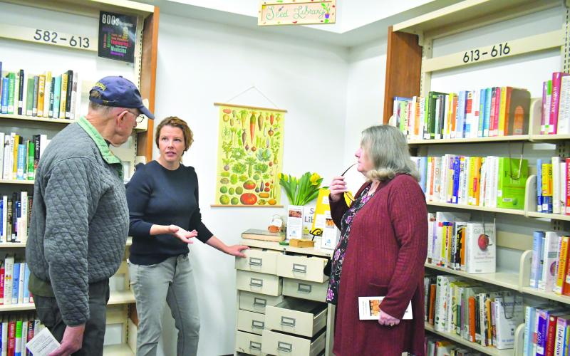 Megan Broome/The Clayton Tribune. April Biagioni (center) talks to David Ruth (left) and Vickie Prater about the Rabun County Seed Library and the different heirloom vegetable, herb, and flower seeds available to the public at the soft opening on March 16.