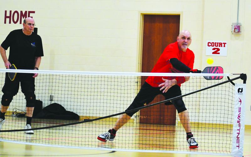 Luke Morey/The Clayton Tribune. Rabun County Recreation Department director Roy Quilliams returns a shot while pickleball partner Danny Burch looks on.