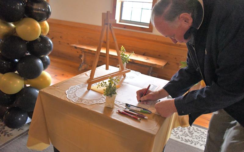 Megan Broome/The Clayton Tribune. Roy DeFoor attends the retirement party for Dr. Guy Gober at Tiger Clinic Friday, March 31, and sings his card with well wishes. Gober has been in Rabun County for 33-and-a-half years but has over 48 years of experience in the medical field.