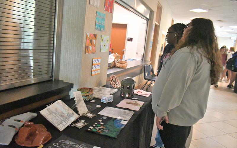 Megan Broome/The Clayton Tribune. Juniors Stella Gonzalez and Brianna Millsap enjoy viewing the artwork at the showcase,