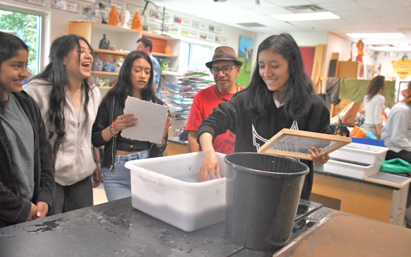 Megan Broome/The Clayton Tribune. Student Jackie Gonzalez makes paper by hand using natural materials and dyes in the art room at Rabun County High School April 21. Artist Javier Silverio, director of Taller Leñateros in Chiapas, Mexico, instructed students on the process, which has roots in Mayan culture. Students look on and have a great time creating the artwork.