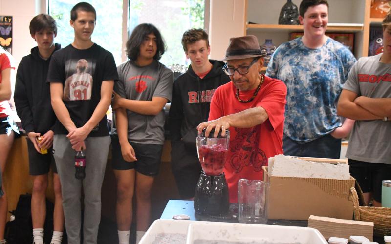 Megan Broome/The Clayton Tribune. Artist Javier Silverio, director of Taller Leñateros in Chiapas, Mexico, instructs students in the Rabun County High School art room April 21 on how to make paper using natural materials and dye. Silverio uses a blender in the process as students look on with excitement.