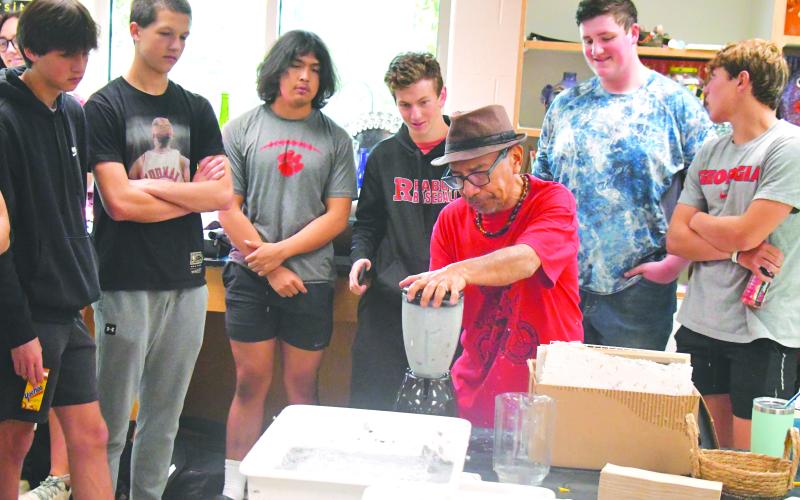 Megan Broome/The Clayton Tribune. Artist Javier Silverio, director of Taller Leñateros in Chiapas, Mexico, instructs students in the Rabun County High School art room April 21 on how to make paper using natural materials and dye. Silverio uses a blender in the process as students look on with excitement.
