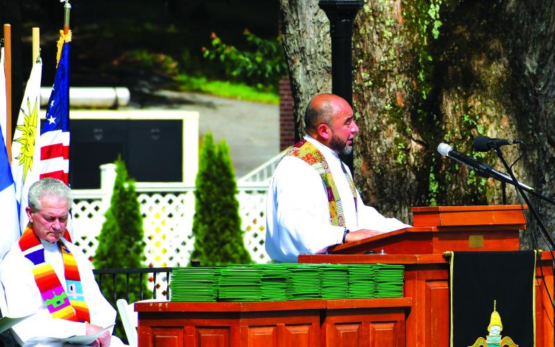 Luke Morey/The Clayton Tribune. With Rev. Jeffry Reynolds in the background, Rabun Gap Rev. Ozu Mejia introduces Rev. Reynolds as the baccalaureate speaker on Sunday, May 21.