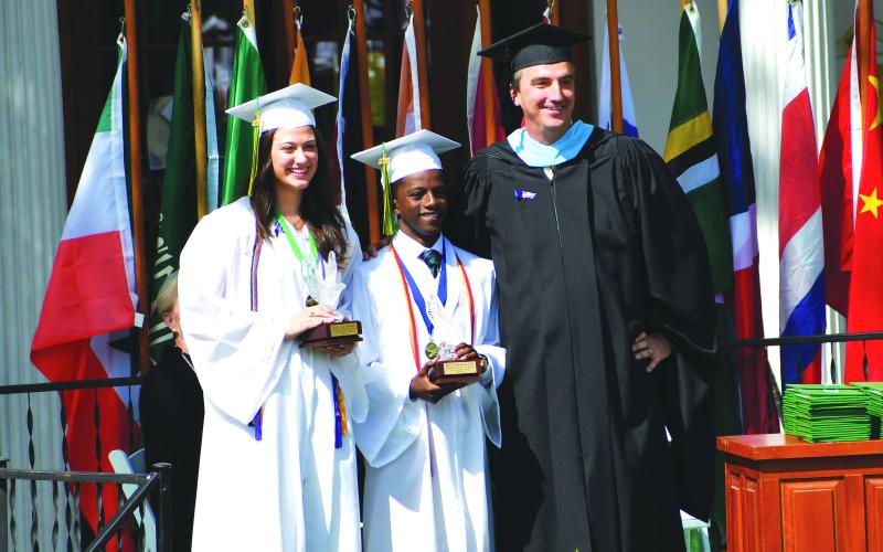 Luke Morey/The Clayton Tribune. During graduation on Sunday, May 21, Rabun Gap Head of School Jeff Miles awards Crystal Eagles to two seniors who exemplify the most school spirit. The award winners were Cheney Moriarty (left) and Benit Jabo.