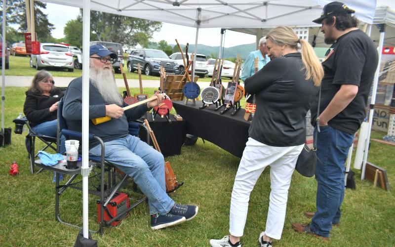 Megan Broome/The Clayton Tribune. Selena Birkbeck and Matt Jones smile with impression as they speak with Les Barnett about his unique Panjo creations at the inaugural Dinglerfest Saturday, May 6. Also pictured is Patti Barnett.