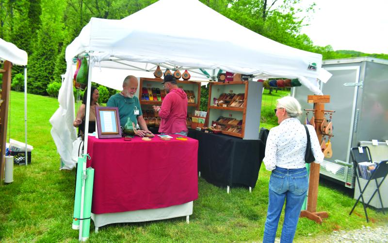 Megan Broome/The Clayton Tribune. Artist Paul Bergstrom with Mountain Melodies is one of the featured artists showcasing his work at the Sassafras Artisan Market April 29-30. A customer eyes the many beautiful creations inside the booth.