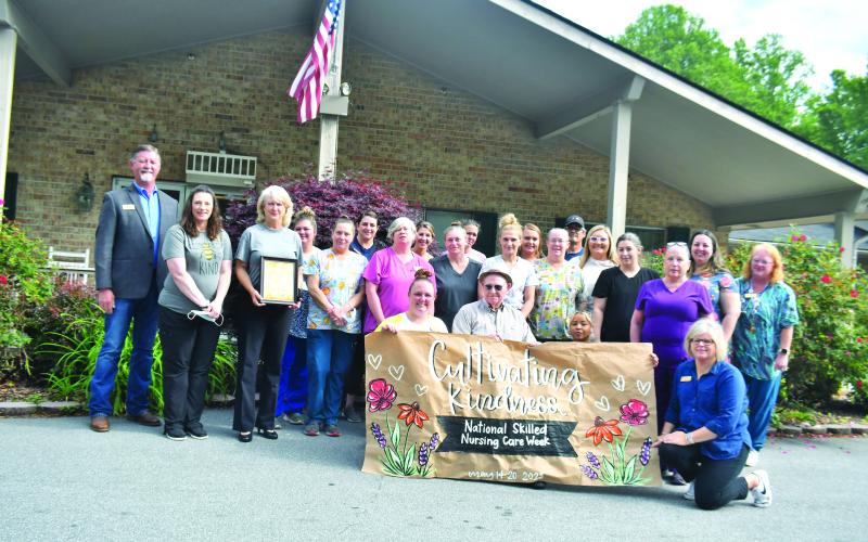 Megan Broome/The Clayton Tribune.  Nurses hold up a sign created by RCHS student Abbye Carver. Resident Ervin Chastain, who turns 100 years old in June, also enjoyed the presentation.