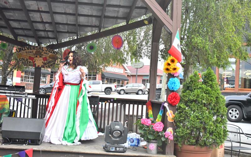 Megan Broome/The Clayton Tribune. Restaurant goers look on as Veronica Trejo, la leyenda hecha voz, performs traditional Mariachi style music at Universal Joint in Clayton to celebrate Cinco de Mayo Friday, May 5. While in traditional dress, Trejo sang and danced and interacted with the crowd as she celebrated the night away on the outdoor stage.