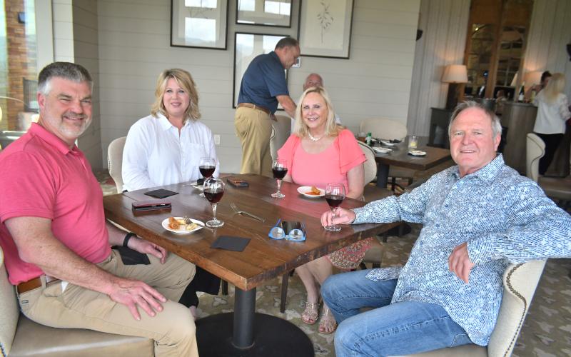 Megan Broome/The Clayton Tribune. District 10 State Rep. Victor Anderson, left; Kim Anderson; LBCA President Elizabeth Gill; and parade Co-Chair Andrew Harris attend the Captain's Reception and planning meeting. Left: Photo courtesy Conner Horn.  Rabun County is the Wooden Boat Capital of Georgia and Lake Burton Wooden Boat owners hold up the sign at the May 12 Captain’s reception.