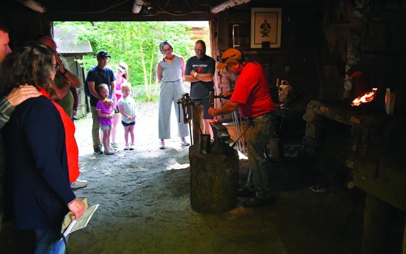 Luke Morey/The Clayton Tribune. Wind Chapman (above) shows visitors how blacksmith work is done.