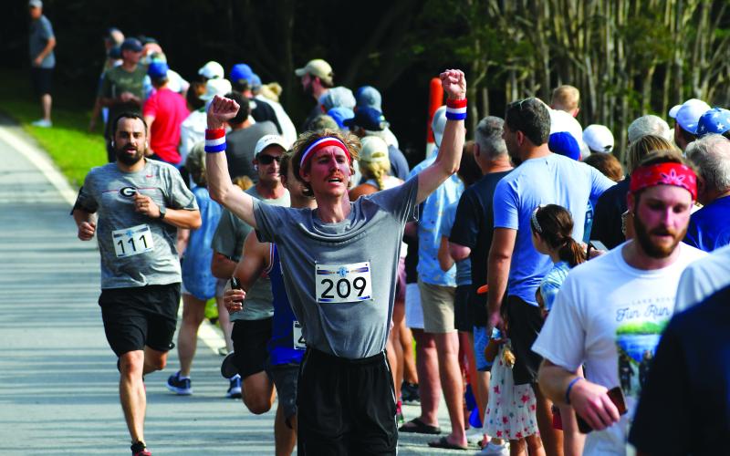 Luke Morey/The Clayton Tribune. Brennan Pope of Vancouver, Wash. raises his fists in victory as he crosses the finish line at the July 1 Lake Burton Fun Run.