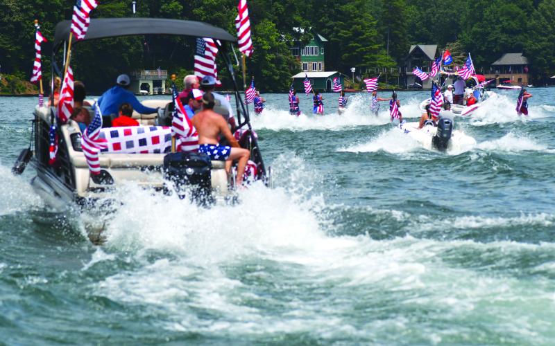 Enoch Autry/The Clayton Tribune. Members of the Ski Patriots wave toward people on balconies of houses on Lake Burton on July 1. In groups, the skiers went around the Rabun County lake for a total of 27 miles. This popular annual event has been putting smiles on individuals’ faces for the past 15 years. This time the youngest skier was 10 years old.