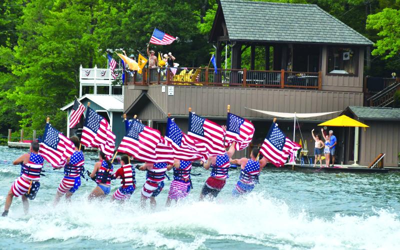 Enoch Autry/The Clayton Tribune. Members of the Ski Patriots wave toward people on balconies of houses on Lake Burton on July 1. In groups, the skiers went around the Rabun County lake for a total of 27 miles. This popular annual event has been putting smiles on individuals’ faces for the past 15 years. This time the youngest skier was 10 years old.