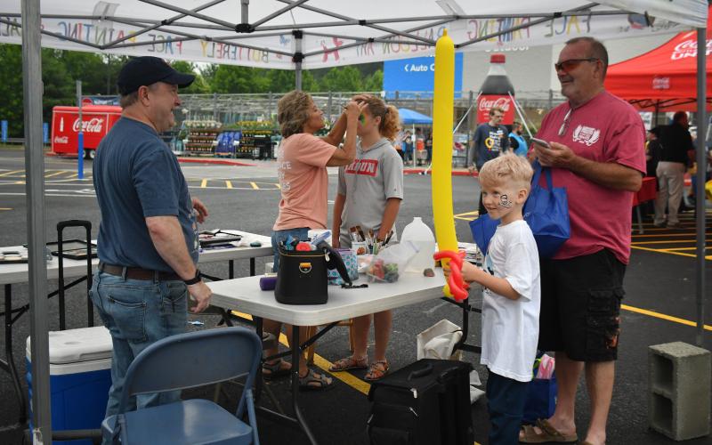 Megan Broome/The Clayton Tribune. Bruce Dale hands Rex Church, 8, a ballon creation during the Walmart grand reopening.