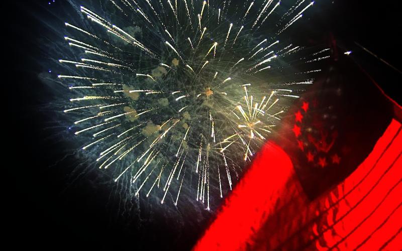 Staff reports/An illuminated marine flag is flown in front of the fireworks at Lake Burton on July 1.