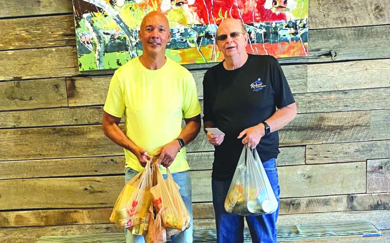 Photo courtesy of Larry Walker. Danny Burch presents the checks and a portion of the food donations to James Brim, manager of the Food Bank of Northeast Georgia Mountain Branch.