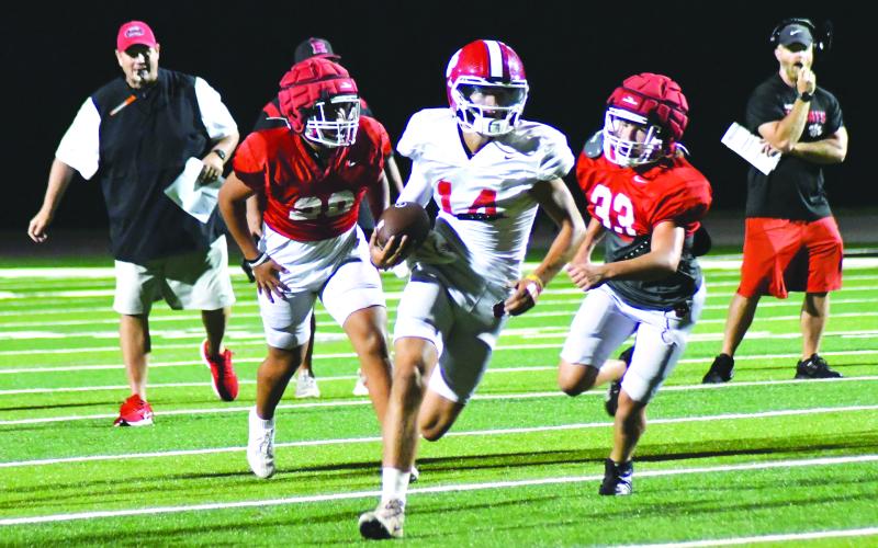 Enoch Autry/The Clayton Tribune. Sophomore starting quarterback Ty Truelove slips through the Wildcat defense for a gainer on the ground as RCHS head coach Michael Davis (left) watches in the background.