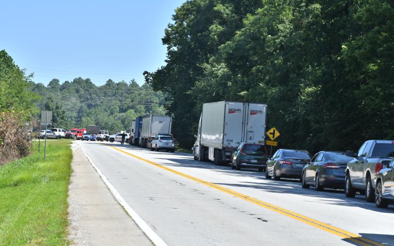 Megan Broome/The Clayton Tribune. Motorists are at a standstill on Highway 441 near Old Highway 441 as all lanes of travel were shut down for hours due to a fatal crash involving a car and tractor trailer. Numerous Rabun County agencies assisted with the crash scene. Left: A memorial with flowers is displayed near the center aisles at the Clayton Ingles that reads “In Memory of Frank Hanrahan.” It also has information about a candlelight vigil that will be held Monday, Aug. 7 at 6:45 p.m.