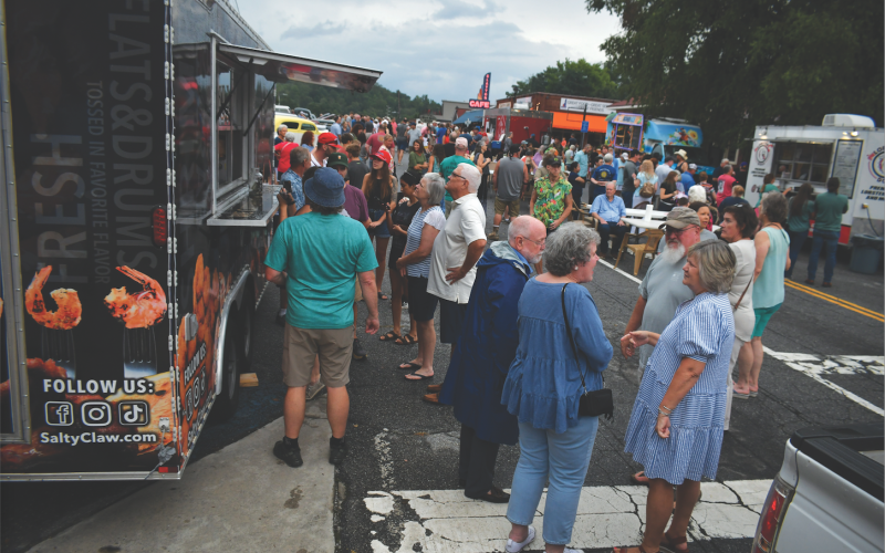 Enoch Autry/The Clayton Tribune.  Before the rain came on Aug. 12 at the downtown block party people congregate on Main Street near the food trucks.