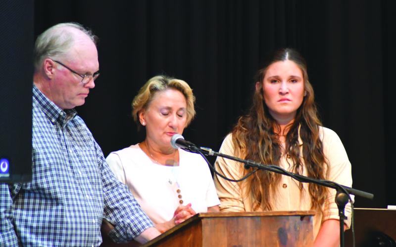 Enoch Autry/The Clayton Tribune. Breck Patterson, Lisa Patterson and their daughter Cylvie stand before the audience at the Rabun County Civic Center to talk about the life of Chan Patterson, a firefighter who died in a boating accident in June 2021 on Lake Tugalo in Rabun County. Search and Rescue consoled the Patterson family. Below:  Sheriff Chad Nichols sits with his 6-year-old son Chatham at the banquet.