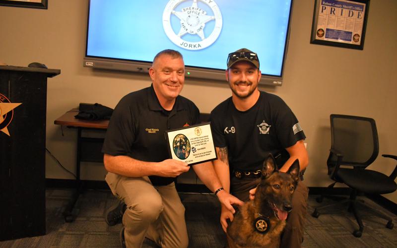 Megan Horn/The Clayton Tribune. Rabun County Sheriff Chad Nichols presents K9 Jorka and partner Cpl. Clinton Scott with a plaque thanking the K9 for six years of honorable service at the Rabun County Sheriff’s Office. K9 Deputy Jorka officially retired September 8.