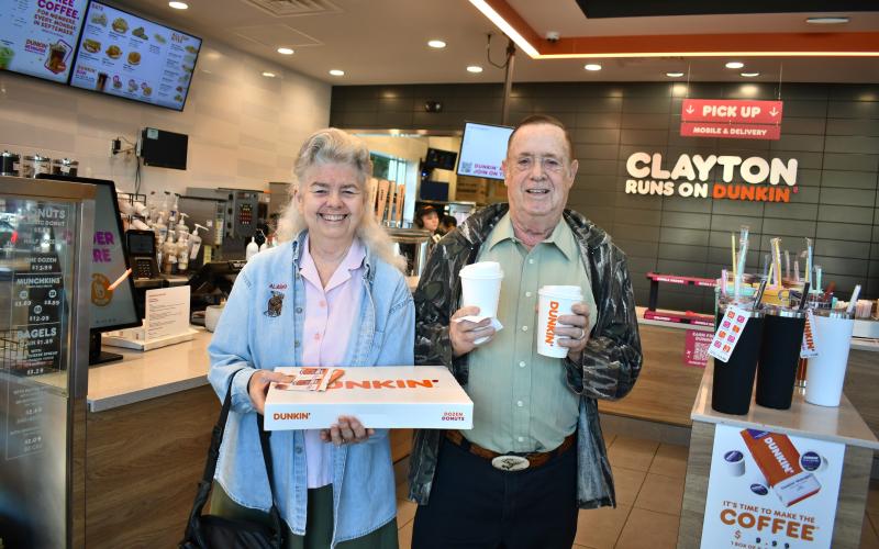 Megan Horn/The Clayton Tribune. Bob and Jean Alexander enjoy doughnuts during the grand opening of Dunkin' Donuts in Clayton Sept. 30. Below: Megan Horn/The Clayton Tribune. Lucy Woerner poses with Cuppy during the Sept. 30 Dunkin' Donuts grand opening.