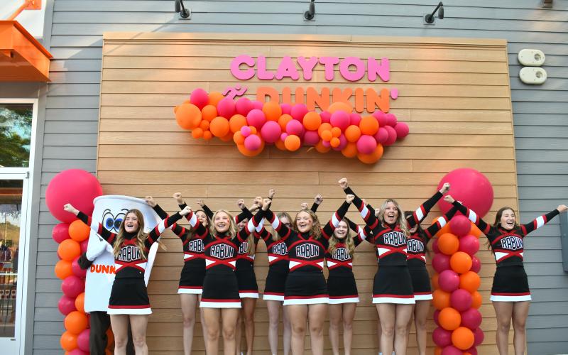 Megan Horn/The Clayton Tribune. Rabun County High School cheerleaders perform a cheer with Cuppy during the Dunkin' Donuts grand opening. Below: Megan Horn/The Clayton Tribune. Lucy Woerner poses with Cuppy during the Sept. 30 Dunkin' Donuts grand opening.