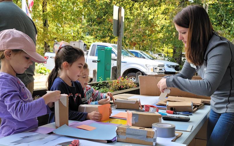 Enoch Autry/The Clayton Tribune. Rabun Gap-Nacoochee chemistry teacher Nicole Ager helps sisters Selah Rouhani, 8; Evelyn Rouhani, 7; and Emily Rouhani, 5, of Clarkesville create pinhole projectors to view the Oct. 11 solar eclipse. People made the trip to the high elevation of Black Rock Mountain State Park to get a better look at the event.