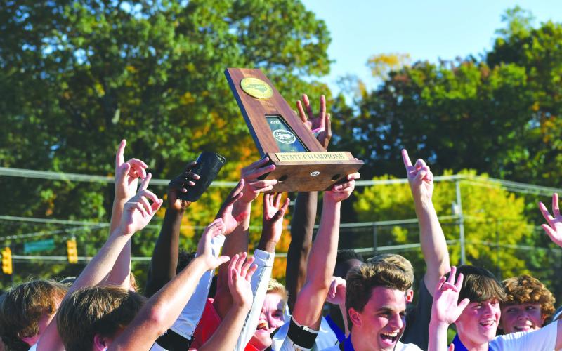Wade Cheek/The Clayton Tribune. RGNS soccer players hoist up the NCISAA State Champion Trophy after their thrilling victory over Wesleyan Christian Academy last Saturday. The victory is the Eagles’ third-straight state title.