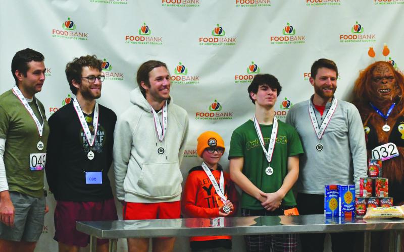 Wade Cheek/The Clayton Tribune. The top finishers of the Clayton Turkey Trot pose for a photo with their medals. Pictured from left to right Matt Lewis, Sam Cohen, Dylan Cohen, Logan Prescott, Joshua Kreiner, Preston Davis and Amber Hunter (Best Costume).