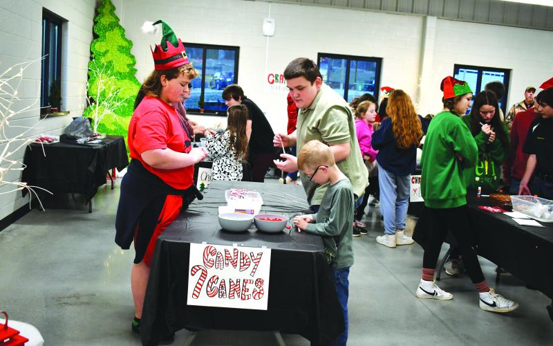 Megan Horn/The Clayton Tribune. FFA member Jayden Daniti with Noah Garrett, 7, and Lee Watkins, 13, at the Candy Cane table.