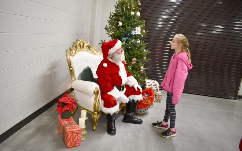 Megan Horn/The Clayton Tribune. Johnna Haas, 9, talks with Santa.