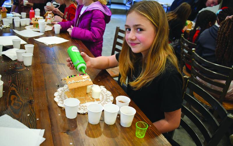 Megan Horn/The Clayton Tribune. Gwindolyn “Winni” Cox, 10, decorates her gingerbread house at the Food Bank of Northeast Georgia Teaching Kitchen.