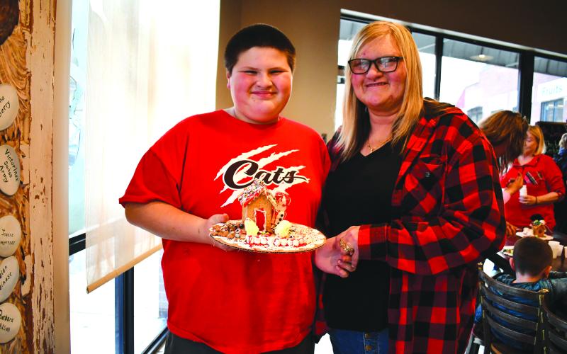 Megan Horn/The Clayton Tribune. Sabrina Baumes and Michael Baumes, 12, show an elaborately decorated gingerbread house at the Food Bank of Northeast Georgia Teaching Kitchen Dec. 13.