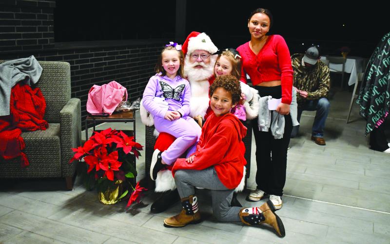 Megan Horn/The Clayton Tribune.  Kinley Burtch, 11; Hudson Hamby, 9; Gypsy Hamby, 5; and Dennie Hamby, 7, are all smiles as they greet Santa and tell him what they want for Christmas because they are on the nice list.