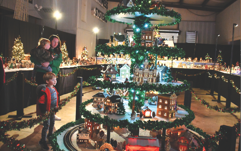 Megan Horn/The Clayton Tribune. The Stille family of Spencer, 1, Jennifer, and Sutton, 4, gaze at the miniature village that includes a train. Left: Five-year-old Ethan Moseley hugs The Grinch at the Village of Lights.