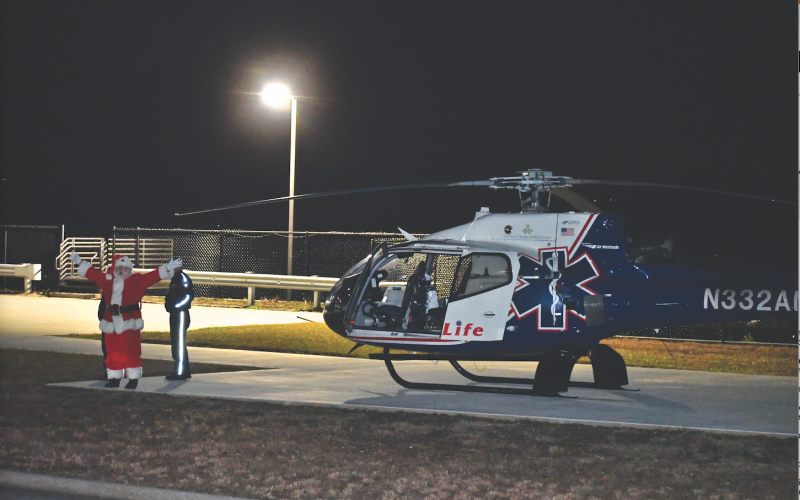 Megan Horn/The Clayton Tribune. Santa arrives at Mountain Lakes Medical Center by helicopter Dec. 14 and waves to a crowd of children jumping up and down in excitement.