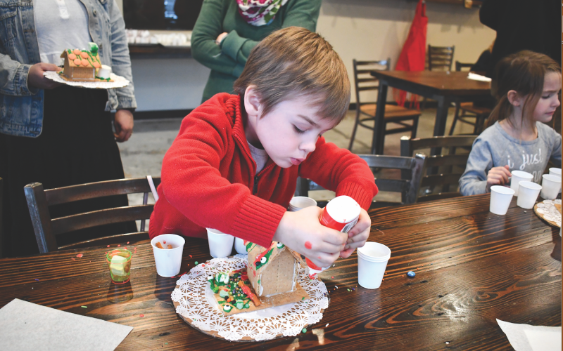 Megan Horn/The Clayton Tribune. Christopher Bramlett, 3, is serious about decorating his gingerbread house at the Food Bank of Northeast Georgia Teaching Kitchen last week.