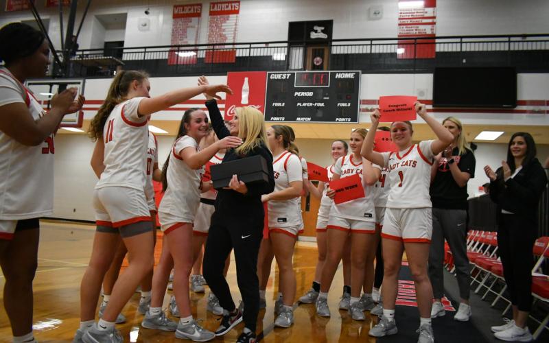 Enoch Autry/The Clayton Tribune. With her Lady Cat players surrounding her, Rabun County girls basketball coach  DeeDee Dillard hugs senior Mili Watts after Dillard logged her 400th career coaching win with a 49-38 triumph over region foe Commerce at home on Jan. 10. Dillard began coaching at RCHS in 2006.
