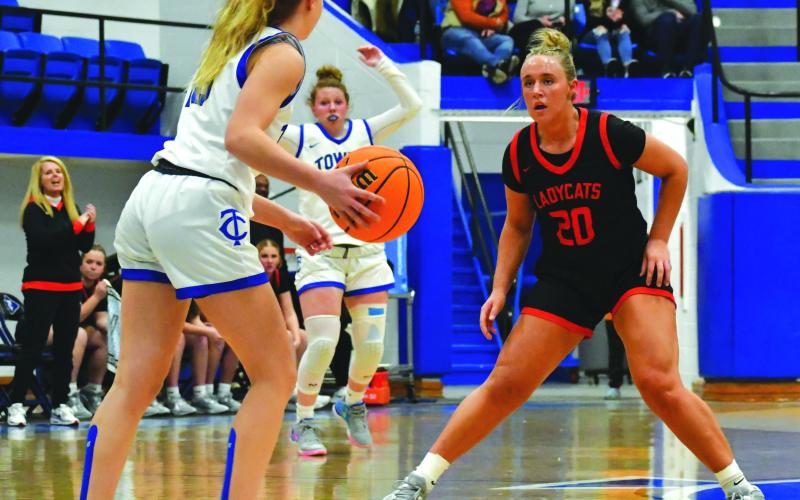 Wade Cheek/The Clayton Tribune. With head coach DeeDee Dillard watching on the left, senior Lady Cat Ellie Southards plays defense against Towns County in December.