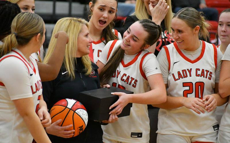 Wade Cheek/The Clayton Tribune. RCHS basketball players surround and celebrate their head coach DeeDee Dillard at mid-court following her 400th career victory as head coach of the Lady Cats.