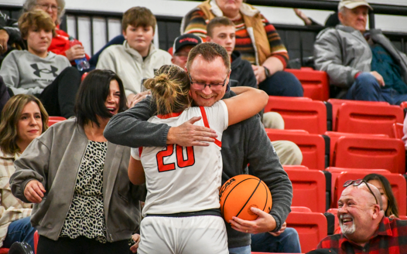 Wade Cheek/The Clayton Tribune. After giving him the game ball from her 1,000th career point, Rabun County Lady Cat senior Ellie Southwards hugs her father Gabe Southarsds in the stands on Jan. 13 at home in Tiger.