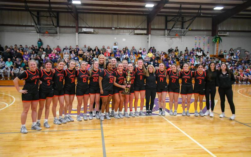 Wade Cheek/The Clayton Tribune. The RCHS girls basketball team stands together with championship hardware after its 57-47 region title victory over Athens Christian.